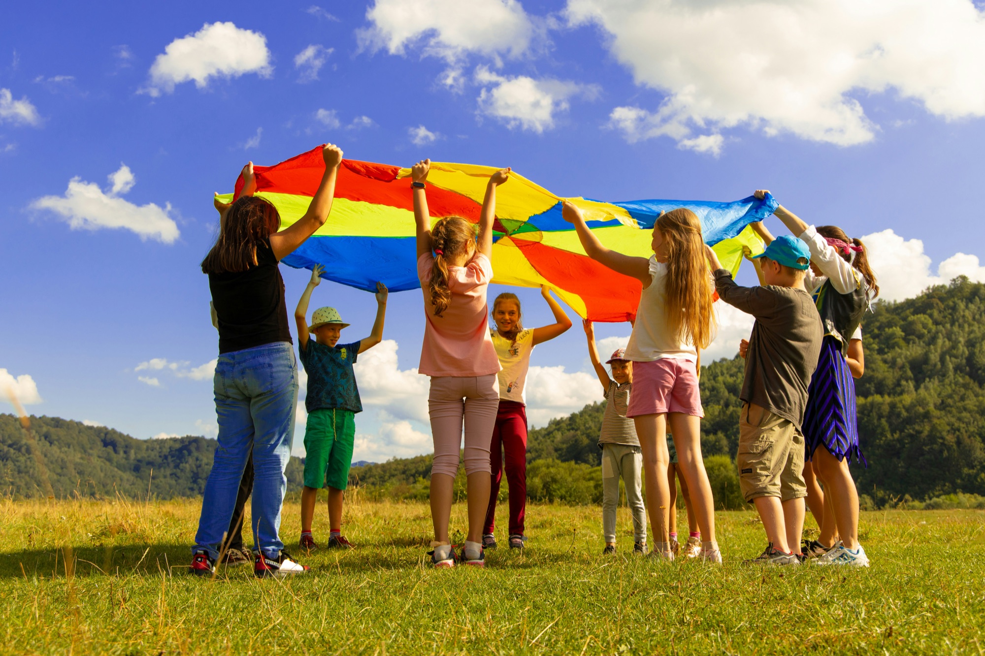 Children playing together outdoors with a colorful parachute